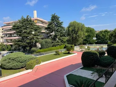 a walkway in front of a building with trees and bushes at Studio bord de mer in Saint-Laurent-du-Var