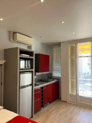 a kitchen with red cabinets and a stainless steel refrigerator at Red studio Buffa in Nice