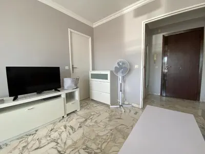 a living room with a flat screen tv and a fan at Stylish Modern Beach Studio in Nice