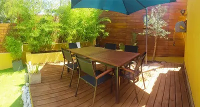 a wooden table with chairs and an umbrella on a deck at Maison Casa Milesa - Calme, Spa privatif sur demande, Parking securisé, à 12 min des plages in Nice