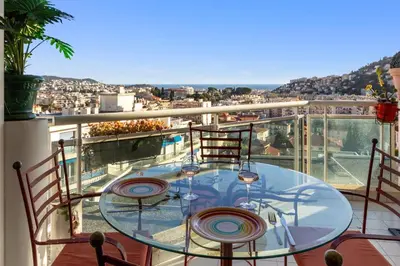 a glass table on a balcony with a view at La Coquette - Sea View - Parking - AC - Pool in Nice