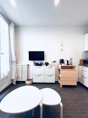 a living room with two white tables and a tv at Studio Cocooning avec terrasse au calme Quartier Les Musiciens Mer à 7 minutes à pieds in Nice