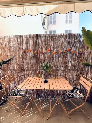 a wooden table and chairs in front of a fence at Studio Cocooning avec terrasse au calme Quartier Les Musiciens Mer à 7 minutes à pieds in Nice