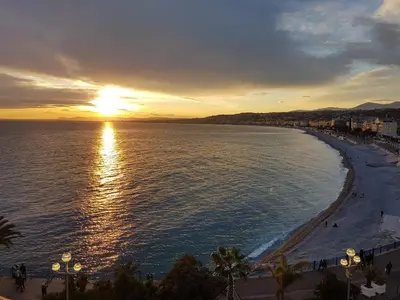 a view of a beach with the sun setting at 