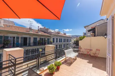 a balcony with an orange umbrella and chairs and tables at Open Sky Terrace Downtown Studio in Nice