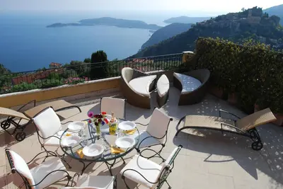 a patio with a table and chairs with a view at Stunning Penthouse with panoramic views of Eze Village and the French Riviera in Èze