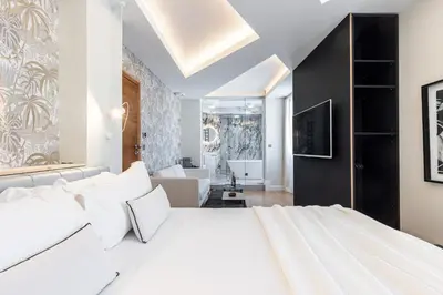 a bedroom with a white bed and a living room at Le Dortoir Boutique Suites in Nice