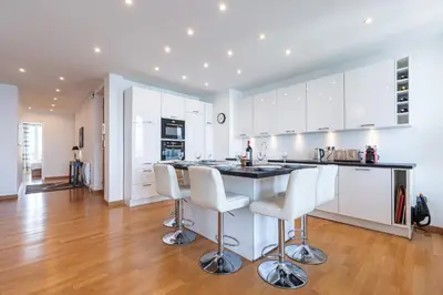 a kitchen with white cabinets and a counter with bar stools at Sea View Large 2 Bdr Promenade des Anglais in Nice