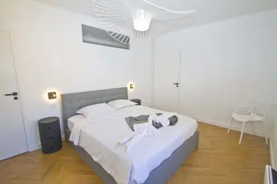 a bedroom with a bed with white sheets and a fan at Holiday Vigie Promenade in Nice