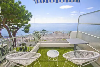 a balcony with two chairs and a table and the ocean at Holiday Vigie Promenade in Nice