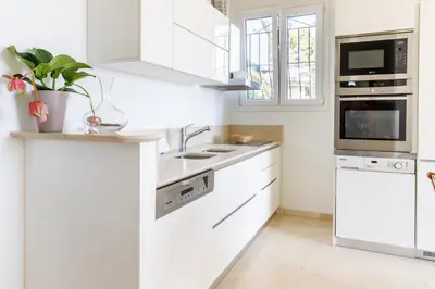 a white kitchen with white cabinets and a sink at Sea View Apartment with Private Secure Parking 1 in Villefranche-sur-Mer
