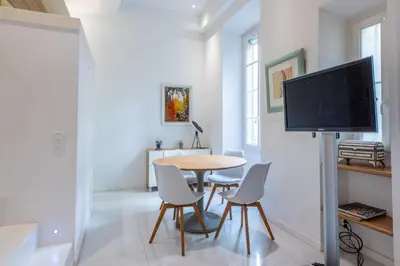 a dining room with a table and chairs and a flat screen tv at Happyfew Liberty in Nice