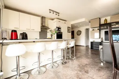 a kitchen with white cabinets and white bar stools at Le Syrius in Nice