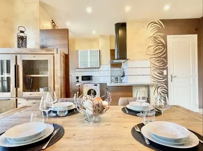 a kitchen with a wooden table with plates and wine glasses at Swiss Star - Easy Home Booking in Nice