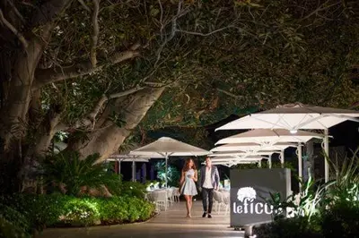 a couple of people walking down a sidewalk with umbrellas at Hotel Cap Estel in Èze