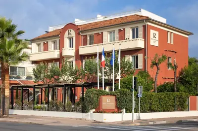 a group of chairs and tables in a garden with flowers at Hotel Royalmar in Cagnes-sur-Mer