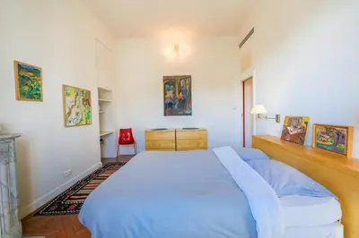 a bedroom with a large bed and a red chair at Victor Hugo Palais AP3061 by Riviera Holiday Homes in Nice
