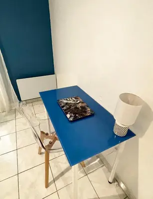 a blue table with a chair and a magazine on it at Joli appartement spacieux à 3 min à pied de la mer in Nice