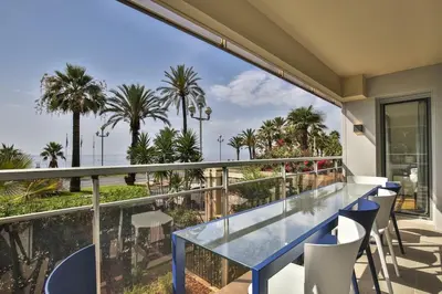 a balcony with a blue table and chairs and palm trees at Sublime Appartement Promenade des Anglais (2) in Nice