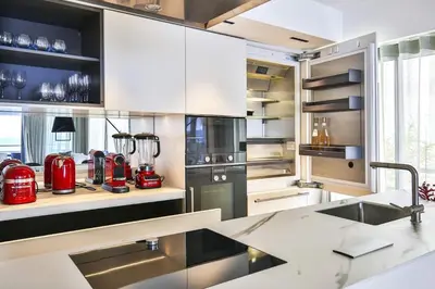a kitchen with white cabinets and red appliances at Sublime Appartement Promenade des Anglais (2) in Nice