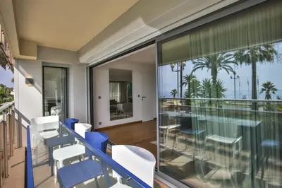 a balcony with blue and white chairs and a view of the ocean at Sublime Appartement Promenade des Anglais (3) in Nice