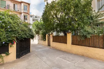 an empty alley with a fence and a tree at On Board Captain in Nice