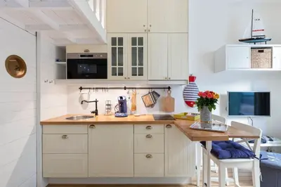 a kitchen with white cabinets and a wooden table at On Board Captain in Nice