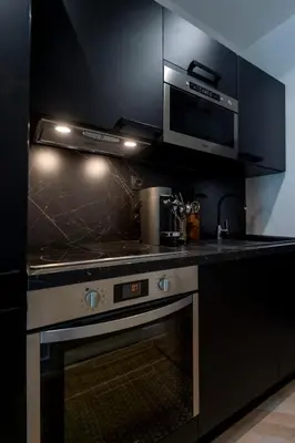 a black kitchen with a stove and a microwave at Superbe studio Plage/Promenade des Anglais 105 in Nice