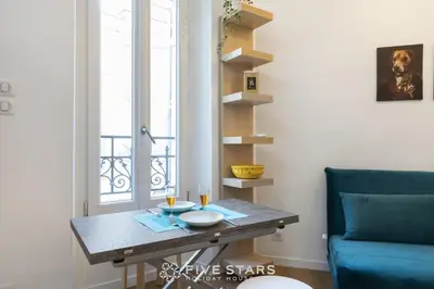 a living room with a table and a blue couch at Studio Fleur FSHH in Nice