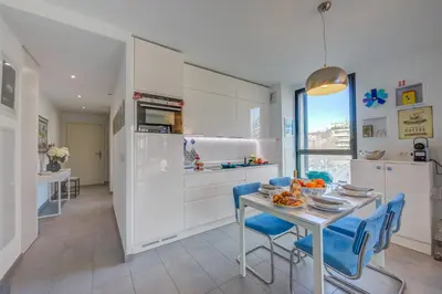 a kitchen with white cabinets and a table with blue chairs at Appartement Liberation in Nice