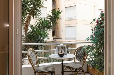 a table and chairs on a balcony with a window at Promenade, 2pièces chic et clim avec terrasse Location éligible au Bail Mobilité Mobility Lease in Nice
