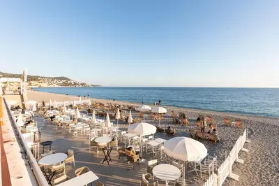 a beach with chairs and umbrellas and people on it at Promenade, 2pièces chic et clim avec terrasse Location éligible au Bail Mobilité Mobility Lease in Nice