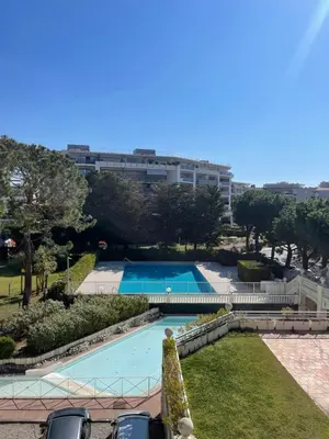 a swimming pool in a park with a building in the background at appartement bord de mer avec piscine in Cagnes-sur-Mer