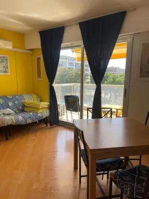 a living room with a table and a couch at appartement bord de mer avec piscine in Cagnes-sur-Mer