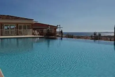 a large pool of blue water in front of a house at L Arieta - Appartement 3 pièces vue mer, parking & piscine in Nice