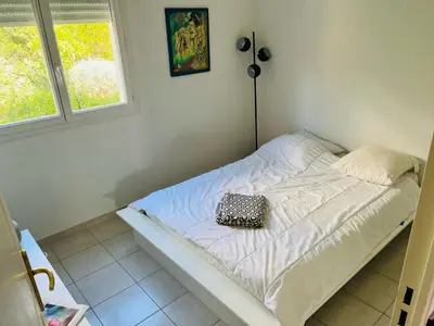 a white bed with a black and white pillow on it at L Arieta - Appartement 3 pièces vue mer, parking & piscine in Nice