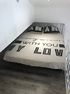 a bed with a black and white comforter and pillows on it at Charmant studio proche mer in Nice