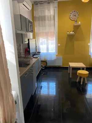 a kitchen with a table and a clock on the wall at Charmant studio proche mer in Nice