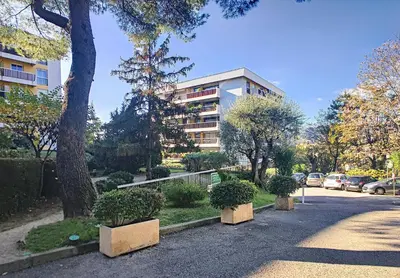 a building with trees and bushes in front of a street at HOME ET HOLIDAY Le Petit Manseng in Nice