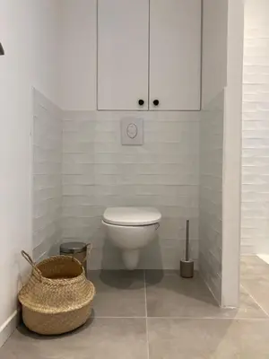 a white bathroom with a toilet and a basket at Habana in Saint-Laurent-du-Var