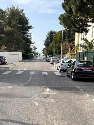 an empty street with cars parked on the road at Habana in Saint-Laurent-du-Var