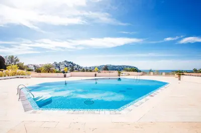 a large swimming pool with blue water in a patio at L'ANGE GARDIEN AP4269 by Riviera Holiday Homes in Villefranche-sur-Mer