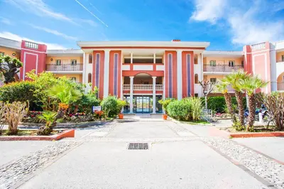 a large building with pink and white columns at L'ANGE GARDIEN AP4269 by Riviera Holiday Homes in Villefranche-sur-Mer
