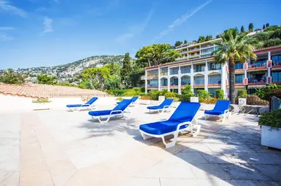 a group of blue lounge chairs and a building at L'ANGE GARDIEN AP4269 by Riviera Holiday Homes in Villefranche-sur-Mer