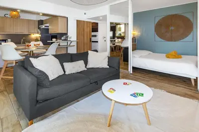 a living room with a couch and a bed and a table at Le Pied Dans L'eau - Parking - Seaside - Hipprodrome in Cagnes-sur-Mer