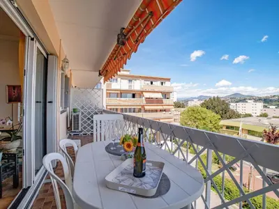 a balcony with a table with a bottle of wine at Apartment Le Giono by Interhome in Saint-Laurent-du-Var