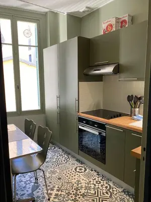 a kitchen with green cabinets and a table with chairs at Suite Alsace Lorraine FSHH in Nice