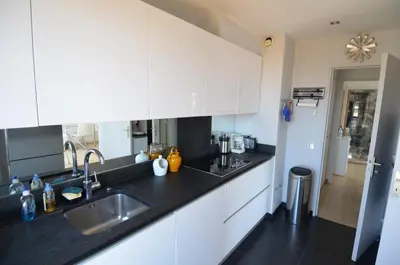 a kitchen with white cabinets and a black counter top at HELIANTHE - Superbe appartement avec terrasse vue mer et Château au Port de Nice in Nice