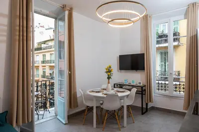 a dining room with a table and chairs and a television at Lovely apartment with terrace Nice centre in Nice