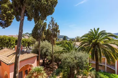 a resort with palm trees and a building at L'ANGE GARDIEN III AP4293 By Riviera Holiday Homes in Villefranche-sur-Mer